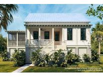 Charming coastal home featuring a white exterior, inviting front porch, and lush tropical landscaping at 7059 Sounding Ln, Johns Island, SC 29455