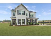 Beautiful two-story home showcasing a well-manicured lawn, stone accents, and black shutters under a bright blue sky at 111 Augusta Pass Dr, Ridgeville, SC 29472