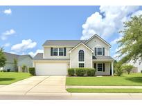 Charming two-story home with a well-manicured lawn and a two-car garage under a blue sky with fluffy white clouds at 113 Rockdale Ln, Goose Creek, SC 29445