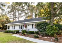 Charming single-story home with a well-manicured lawn, inviting walkway, and an American flag at 1351 Winifred St, Mount Pleasant, SC 29464