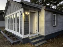 Charming home entrance with gray siding, bright lights, and steps leading to the front door at 1488 Remount Rd, North Charleston, SC 29406