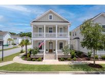 Charming two-story home featuring a double porch, lush landscaping, and an American flag at 1535 Low Pk St, Mount Pleasant, SC 29464