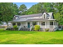 Charming two-story home featuring a welcoming front porch, solar panels, and a lush green lawn at 162 Whippoorwill Dr, Summerville, SC 29483