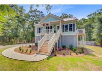 Charming two-story beach house with a welcoming porch and lush landscaping at 18 Tupelo Trl, Edisto Island, SC 29438