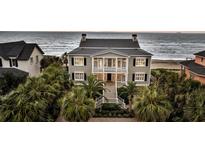 Elegant beachfront home featuring a charming front porch, palm trees, and picturesque ocean views at 210 Ocean Blvd, Isle of Palms, SC 29451