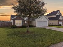 Charming single-Gathering home with a well-manicured lawn and mature tree in a suburban neighborhood at sunset at 224 Market Hall St, Moncks Corner, SC 29461