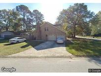Charming two-story brick home featuring an attached two-car garage and a well-maintained front lawn at 8194 Courtwood Rd, North Charleston, SC 29406