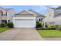 Charming home featuring a two-car garage, yellow front door, and well-maintained landscaping at 9712 Fanning Basket Ln, Ladson, SC 29456