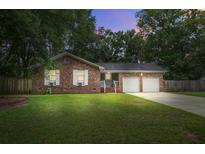 Charming brick home featuring a two-car garage, well-manicured lawn, and mature trees at dusk at 110 Terry Ave, Summerville, SC 29485