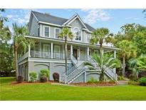 Charming two-story home with a wrap around porch, staircase entry, and lush, green landscaped yard at 1447 Headquarters Plantation Dr, Johns Island, SC 29455