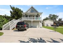 Charming raised beach house with a double garage, spacious driveway, and a welcoming front porch at 1625 Teal Marsh Rd, Charleston, SC 29412