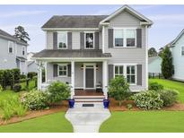 Charming two-story home with gray siding, shuttered windows, manicured lawn and a welcoming front porch with tasteful decor at 3998 Capensis Ln, Ravenel, SC 29470