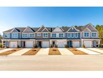 New townhomes boast varying blue hues, well-manicured lawns and convenient attached garages at 424 Duskywing Dr, Goose Creek, SC 29445