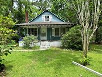 Charming bungalow-style home with a cozy front porch and verdant lawn surrounded by mature trees at 1640 Dogwood Rd, Charleston, SC 29414