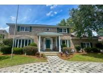 Charming two-story brick home with a welcoming front porch, manicured landscaping, and beautiful driveway at 1866 Capri Dr, Charleston, SC 29407