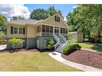 Charming home featuring a screened front porch with white railings, a gray foundation, and mature landscaping at 2649 Starfish Dr, Johns Island, SC 29455