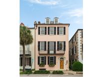 Charming pink three-story house featuring black shutters, window boxes, and a classic wooden front door at 55 E Bay St, Charleston, SC 29401