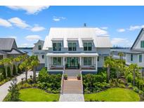 Stunning two-story home with metal roof, inviting front porch, meticulous landscaping, and vibrant green lawn at 553 Old Compass Rd, Daniel Island, SC 29492