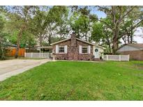 Charming brick home features a well-manicured lawn, mature trees, and a classic white picket fence at 10 Teaneck Rd, Goose Creek, SC 29445
