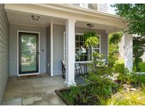 Charming front porch with plants, decor and a cozy seating area welcomes you home at 108 Plume Poppy Ln, Ladson, SC 29456