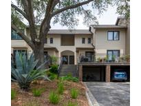 Exterior view of a multi-story condo building featuring covered parking, stairs to the units, and mature landscaping at 1919 Marsh Oak Ln, Seabrook Island, SC 29455
