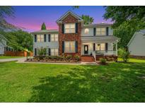 Charming two-story home with a lush green lawn and colorful flowerbeds at dusk at 2026 Thornhill Dr, Summerville, SC 29485