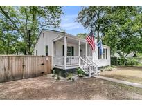 Charming home showcasing a cozy front porch, complemented by a manicured landscape and fresh, white paint at 2666 Poplin Ave, North Charleston, SC 29405