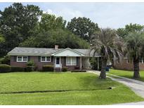 Charming one story brick home with mature landscaping, green lawn, and a paved driveway at 2734 Mona Ave, Charleston, SC 29414