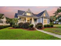 Charming two-story home featuring a cozy front porch and a well-manicured lawn with beautiful landscaping at 401 Felders Ln, Johns Island, SC 29455