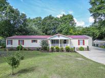 Charming single-story home with a well-manicured lawn, lush landscaping, and a welcoming front porch at 617 Deepwood Ct, Moncks Corner, SC 29461
