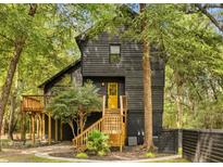 Charming two-story home with a wooden porch and yellow door nestled among mature trees at 6464 Saint Anthony Dr, Meggett, SC 29449