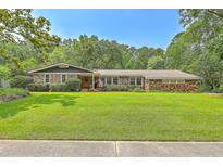 Beautiful brick home featuring a manicured lawn, mature trees, and a welcoming entrance at 133 Axtell Dr, Summerville, SC 29485