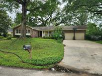 Charming single-story brick home featuring a well-manicured lawn, mature trees, and a two-car garage at 1389 Parkshore Dr, Charleston, SC 29407