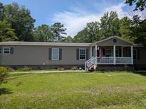 Charming one-story home featuring a cozy front porch, green lawn, and beautiful landscaping at 215 Hines Dr, Bonneau, SC 29431