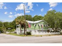 Charming two-story home with light green exterior, white picket fence, and a beautifully landscaped front yard at 2218 Myrtle Ave, Sullivans Island, SC 29482