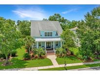 Inviting two-story home features a charming front porch and a beautifully landscaped front yard with mature trees at 2800 River Vista Way, Mount Pleasant, SC 29466