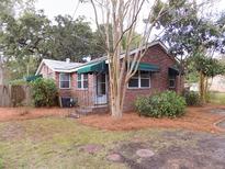 Charming brick home featuring awnings, landscaped front yard, and a cozy, welcoming entrance at 3034 Maybank Hwy, Johns Island, SC 29455