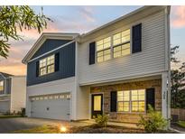 Two-story home with blue and white siding, stone accents, a two-car garage, and well-maintained landscaping at 304 Torslanda Ln, Summerville, SC 29486