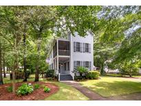 Charming two-story home features a welcoming porch, a meticulously landscaped yard, and mature trees enhancing its curb appeal at 5152 Coral Reef Dr, Johns Island, SC 29455