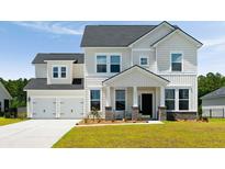 Charming two-story home featuring a two-car garage, inviting porch, and manicured lawn at 7011 Pumpkinseed Dr, Johns Island, SC 29455