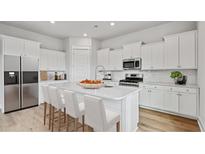 Modern kitchen featuring white cabinets, stainless steel appliances, and a quartz countertop island with bar seating at 89 French Garden Cir, Summerville, SC 29486