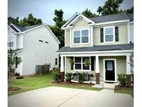 Charming home boasts a well-manicured lawn, complemented by lovely landscaping and a cozy front porch seating area at 9101 Parlor Dr, Ladson, SC 29456