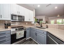 Well-lit kitchen featuring stainless steel appliances, modern tile backsplash, and gray and white cabinets at 1121 Basildon Rd, Mount Pleasant, SC 29466
