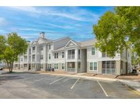 Attractive condo building with beige siding, white trim, screened porches, reserved parking, and mature landscaping at 130 River Landing Dr # 9104, Charleston, SC 29492