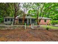 Charming brick home with a white picket fence and mature trees in a serene setting at 1384 Tibwin Rd, McClellanville, SC 29458