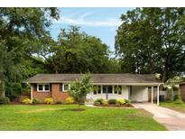 Charming brick and white home featuring mature trees and a well-manicured lawn at 1417 Downing St, Charleston, SC 29407