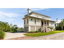 Charming two-story beach home featuring a covered porch, and a well-manicured lawn at 2618 Raven Dr, Sullivans Island, SC 29482