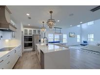 Bright, open-concept kitchen with white cabinets, quartz countertops, stainless appliances, and elegant pendant lighting at 4374 Cotton Flat Rd, Summerville, SC 29485