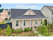 Charming single-story home featuring a welcoming front porch, pink front door, and lush landscaping at 703 Blueway Ave, Summerville, SC 29486