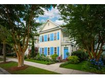 Charming two-story home with yellow siding, blue shutters, and a beautifully landscaped front yard at 907 High Nest Ln, Charleston, SC 29412